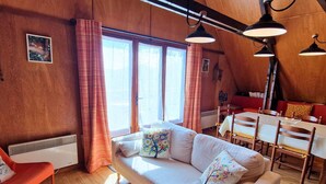 Una habitación acogedora con un sofá, una mesa de comedor y una silla roja.