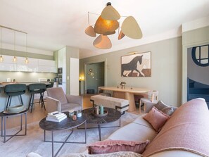 A modern living room with a sofa, coffee table, and chairs, a dining area with a table and chairs, and a kitchen with cabinets and appliances. - Ideal apartment, pets allowed, city centre (Le Touquet-Paris-Plage)