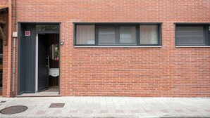 Un edificio de ladrillo rojo con puerta, ventanas y un pequeño espacio al aire libre.