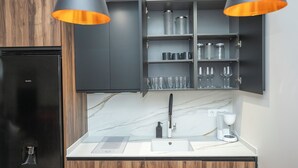 Una cocina moderna con un refrigerador negro, armarios de madera, encimera de mármol y dos lámparas colgantes.