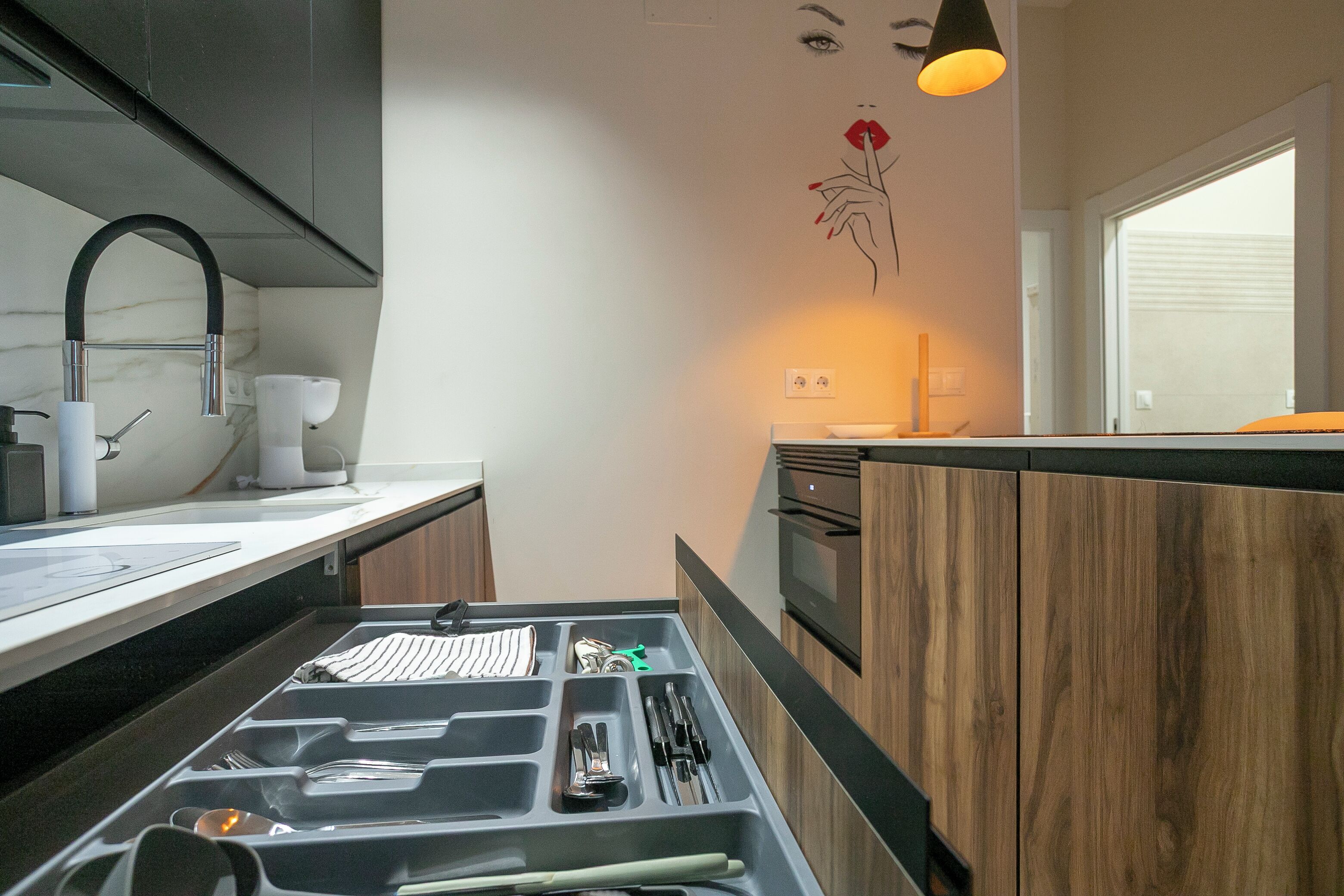 A modern kitchen with a built-in oven, a sink, and a wooden countertop.