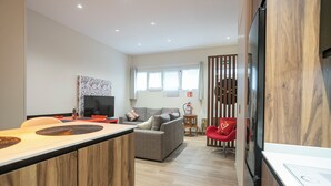 Una sala moderna con un sofá, un televisor y una zona de comedor con una mesa de madera.