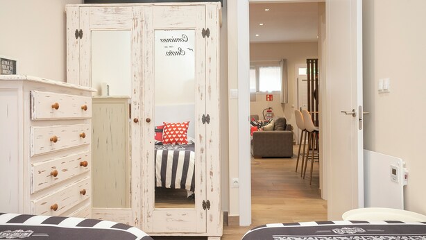Un dormitorio con cama, armario y puerta que da a una sala de estar.