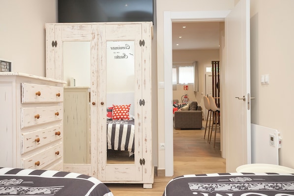 A bedroom with a bed, a wardrobe, and a door leading to a living area.