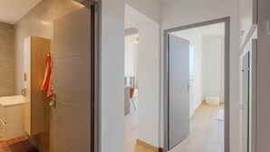 A modern interior with a bathroom, a hallway, and a visible kitchen area. - Maison Mon Idée | Top floor, Bright, sea view and Palais des Festivals (Cannes)