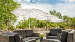 Een terras met rieten meubels en witte parasols.