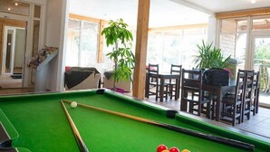 Ett biljardbord med bollar, en matplats med stolar och en trappa som leder till ett annat rum.