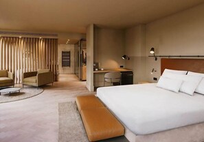 A modern hotel room with a large bed, a desk, a chair, and a sofa. - Eurostars Andorra (Andorra la Vella)