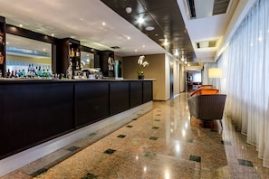 Een moderne hotel lobby met een bar, een zithoek en een uitzicht op de lobby.