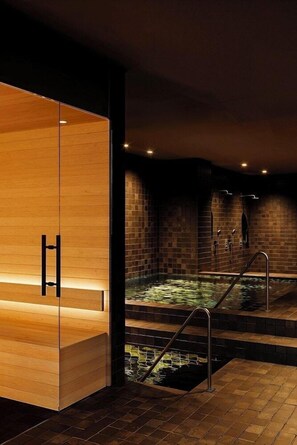 Un área de spa con un mostrador de recepción de madera, una bañera de hidromasaje y paredes con azulejos.