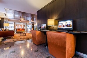Un vestíbulo moderno con mostrador de recepción, zona de estar y una gran pantalla de televisión.