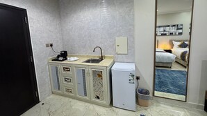 Habitación de hotel compacta con kitchenette, una cama, un espejo grande y vista al interior de la habitación.