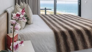 Ein modernes Schlafzimmer mit einem großen Bett, Meerblick und einer Topf-Orchidee.
