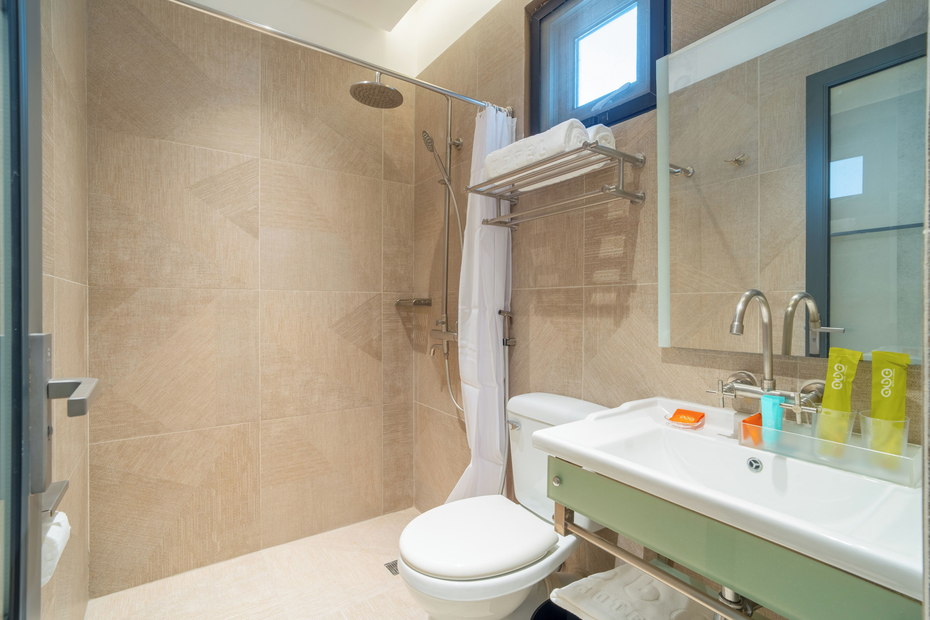 Un baño con ducha, inodoro, lavamanos y barra para toallas.