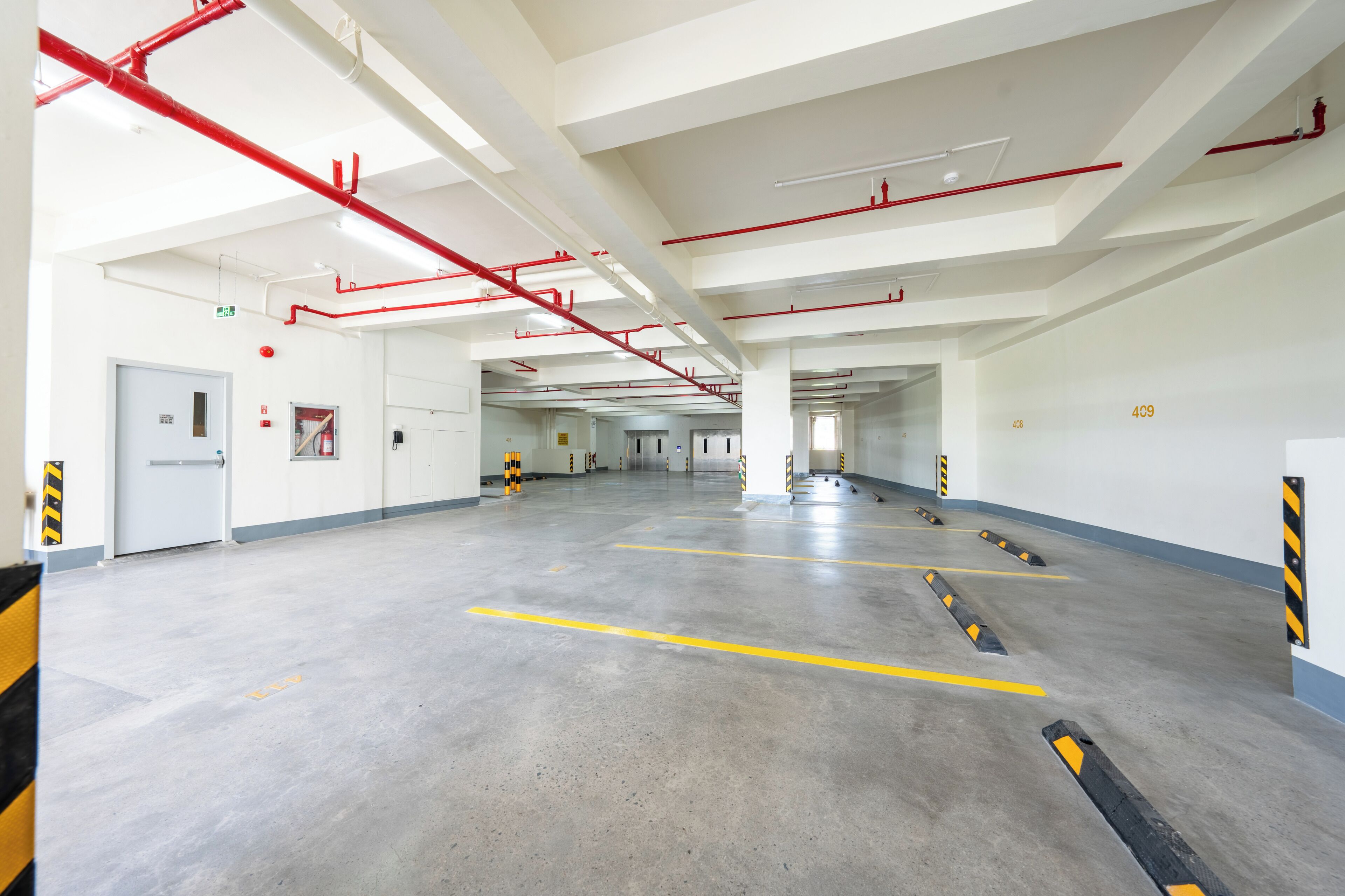 A spacious indoor parking area with clear signage, emergency exits, and a clean, well-maintained floor.