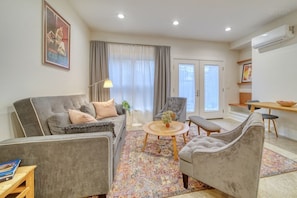 Ein modernes Wohnzimmer mit grauem Sofa, Sesseln, einem Couchtisch und einem gemusterten Teppich.