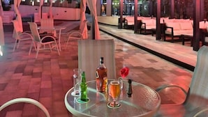An outdoor patio area with tables and chairs, a covered seating area, and a building in the background. - Hotel De Leopol International (Addis Ababa)