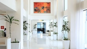 A spacious hotel lobby with a high ceiling, large windows, and potted plants. - Hotel De Leopol International (Addis Ababa)
