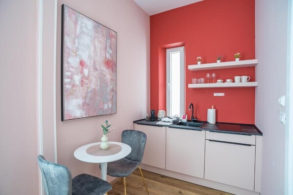 Una cocina moderna con armarios blancos, encimera negra y una pared de acento roja.