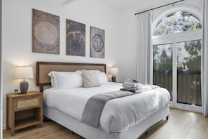 A hotel room with a large bed, two bedside tables with lamps, and three framed artworks on the wall. - The Accessible Atom | Historic Main (Saint Charles)