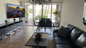 Ein modernes Wohnzimmer mit Fernseher, Sofa, Couchtisch und Essbereich.