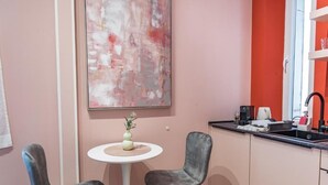 A small kitchenette with a white countertop, a sink, and a coffee machine. There are two grey chairs and a small round table with a vase. - Prime City Center Studio in Split - Walk to Diocletian's Palace (Split)