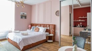 A bedroom with a bed, bedside tables, a nightstand, a mirror, a window, and a view of a kitchen. - Prime City Center Studio in Split - Walk to Diocletian's Palace (Split)