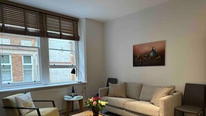Ein Wohnzimmer mit Sofa, Sesseln, Couchtisch und einem Bild an der Wand.
