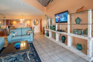 A living room with a sofa, coffee table, and a TV mounted on the wall.