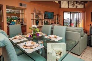 A dining area with a glass table, chairs, and a view of the outdoors.