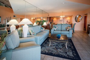 A living room with two sofas, a coffee table, and a dining area in the background.
