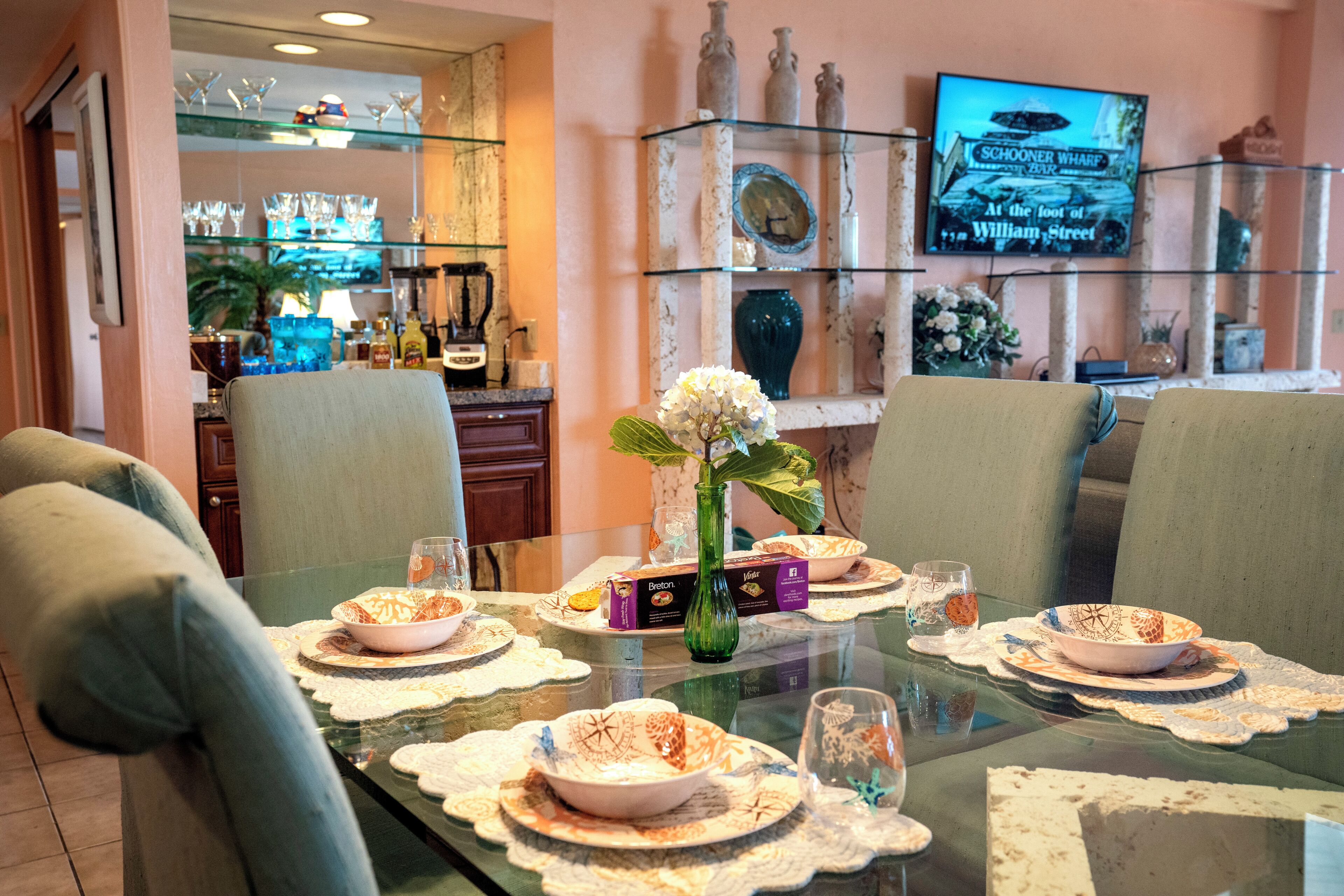 A dining table set with plates, bowls, and glasses, surrounded by chairs.