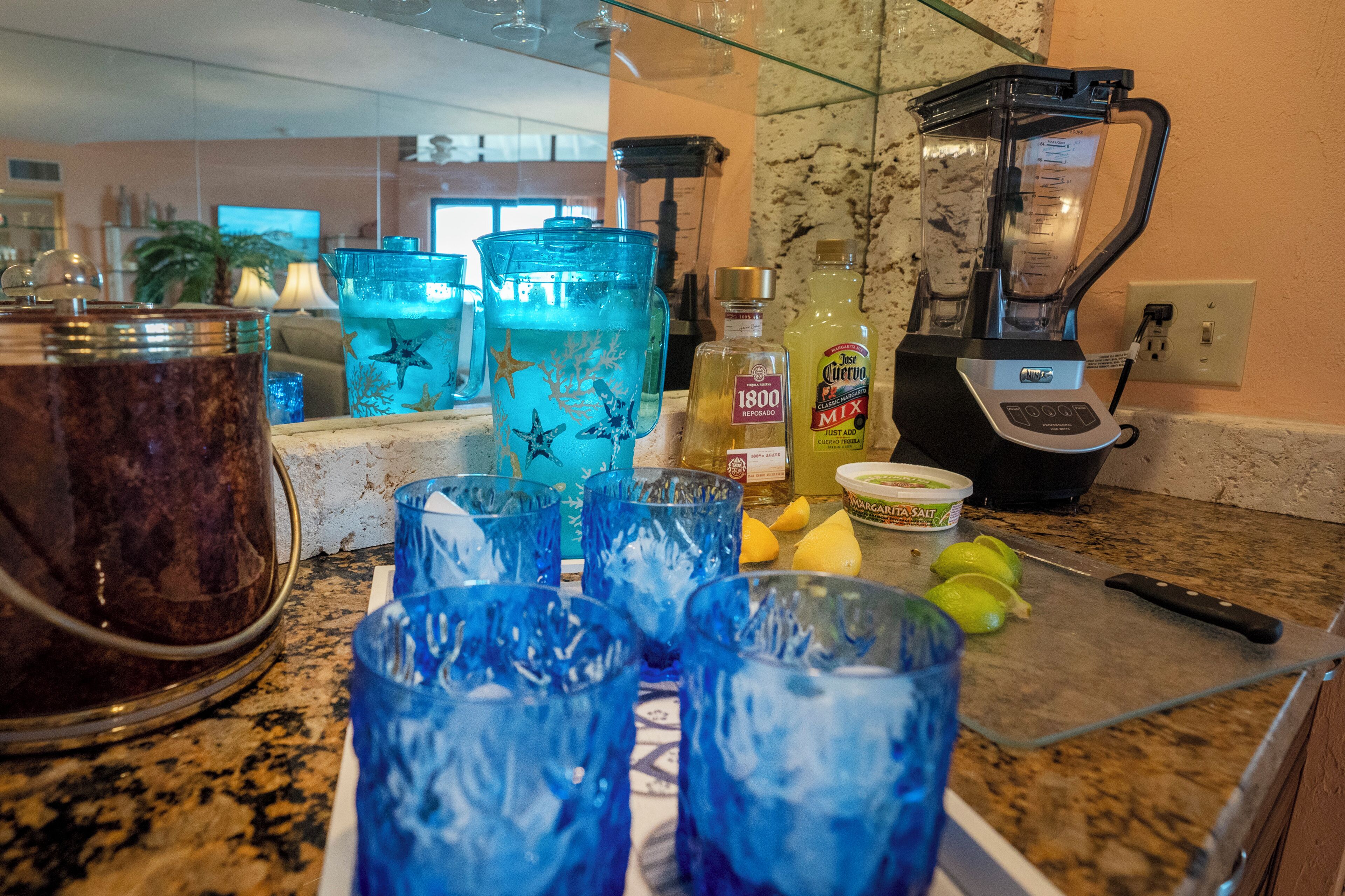 Una encimera de cocina con una licuadora, vasos y una tabla de cortar con limones.