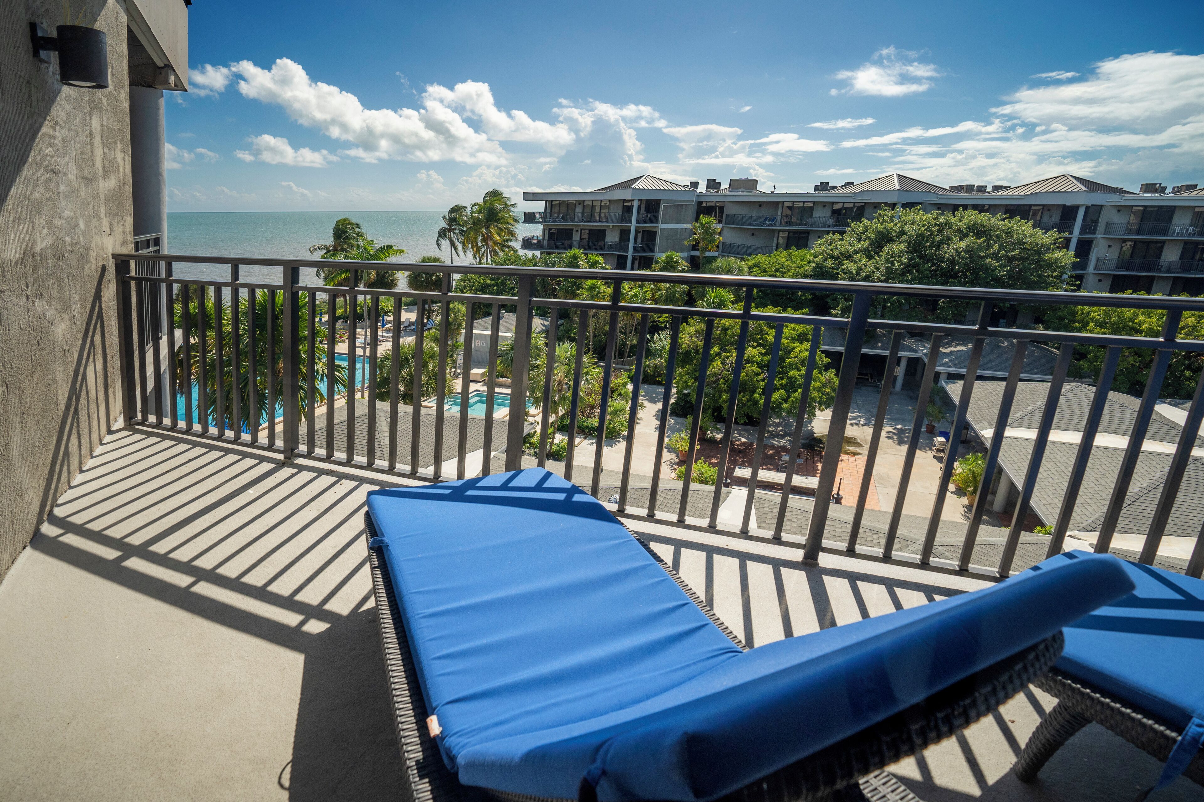 A balcony with a view of the ocean and a pool area.