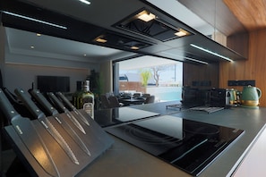A modern kitchen with a built-in stove, a knife block, and a view to the outdoors. - Designer Villa with Heated Pool on Santa Rosalia Lake Resort (Torre-Pacheco)