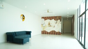 A spacious room with a modern design, featuring a blue sofa, a wall mural, and a ceiling fan.