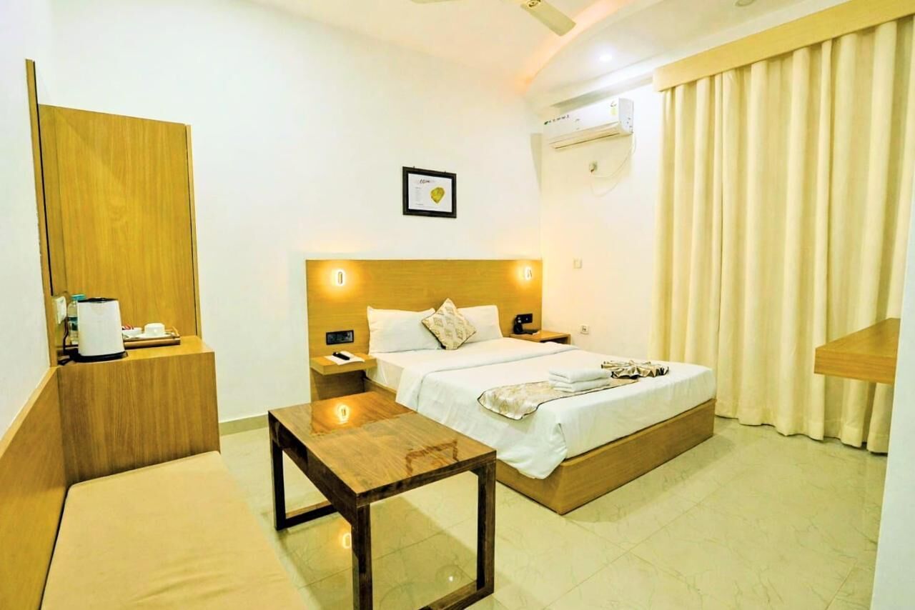Une chambre d’hôtel comprenant un lit, des tables de chevet, une petite table, une armoire en bois et un climatiseur fixé au mur.