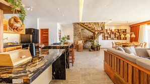 A modern kitchen with granite countertops, a central island, and a hanging plant. - Beachfront retreat in Preá, with pool, rooftop, massage room and gym. (Caiçara)