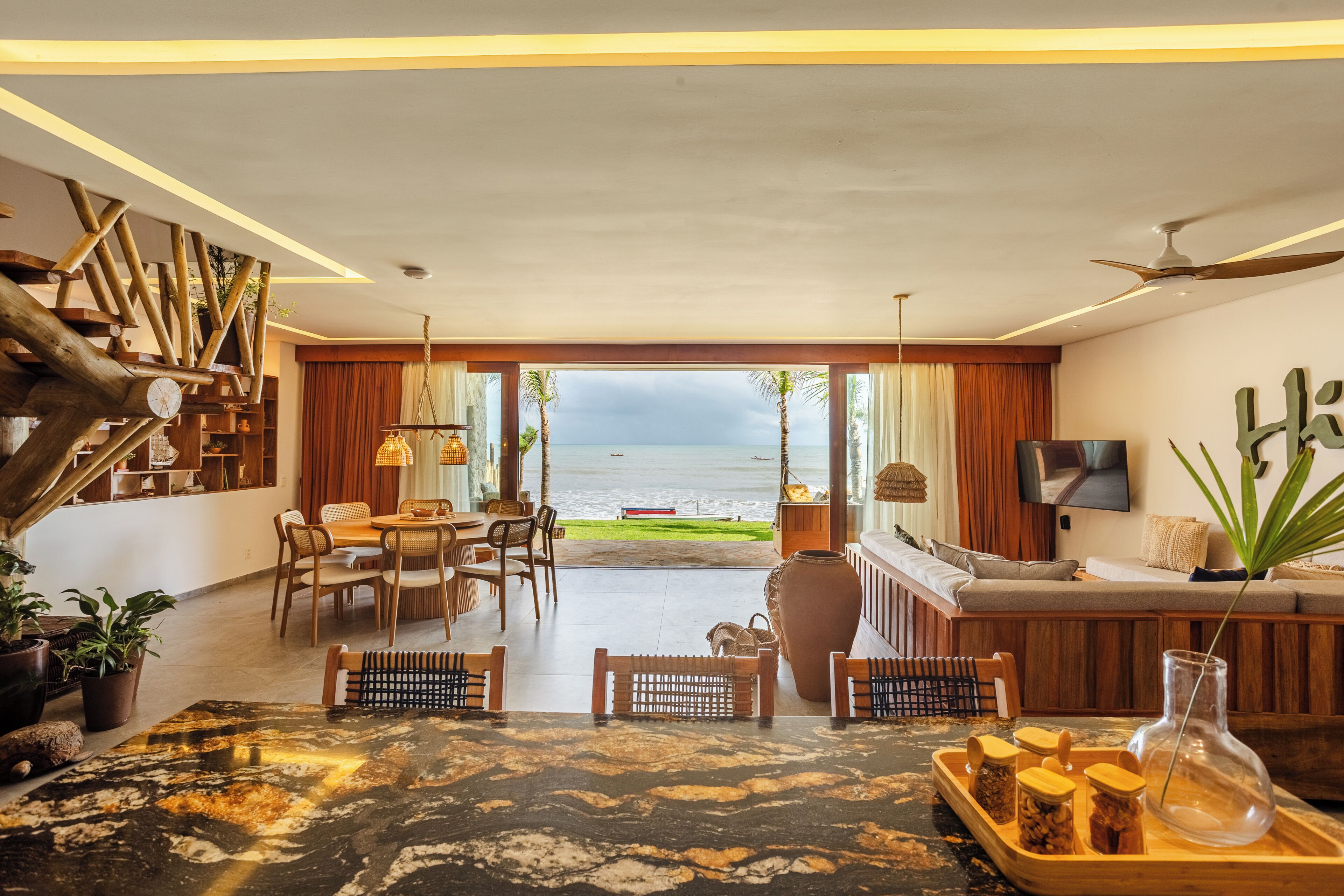 A spacious living area with a view of the sea, wooden furniture, and a modern design.