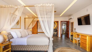 A bedroom with a four-poster bed, a bedside table, a TV, a desk, and a chair. - Beachfront retreat in Preá, with pool, rooftop, massage room and gym. (Caiçara)