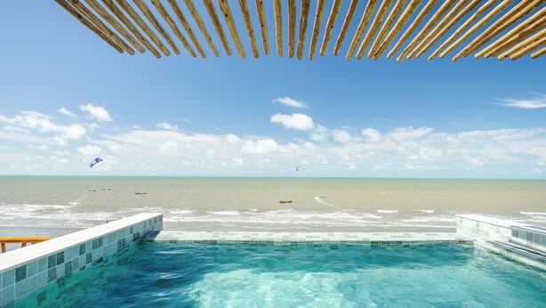 A clear blue pool with a wooden deck and a view of the beach and ocean. - Beachfront retreat in Preá, with pool, rooftop, massage room and gym. (Caiçara)
