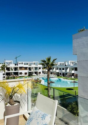 A modern hotel with a pool, palm trees, and a clear blue sky. - Condo with solarium in Laguna Beach Resort In Los Balcones in Torrevieja (Torrevieja)