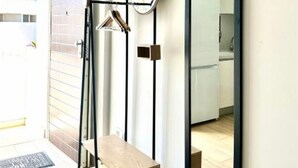 Een moderne badkamer met een houten bankje, een spiegel en een handdoekhouder.