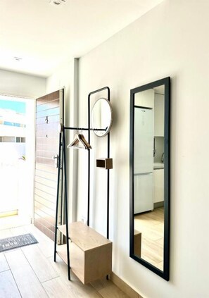 A modern bathroom with a wooden bench, a mirror, and a towel rack. - Condo with solarium in Laguna Beach Resort In Los Balcones in Torrevieja (Torrevieja)