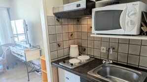 Ett kompakt kök med mikrovågsugn, diskho och ett litet kylskåp.