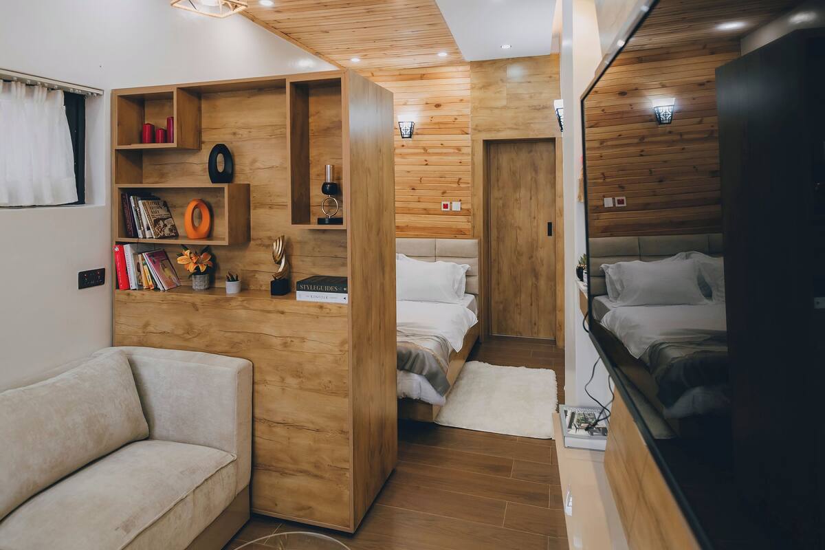 A modern interior with a sofa, a round coffee table, a bed, and a TV.