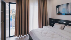 A modern hotel room with a large bed, a sliding glass door to a balcony, and a painting on the wall. - Misteph Luxury Living (Kigali)