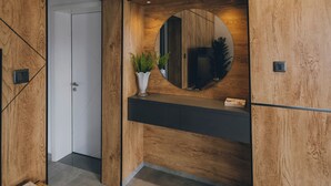 A modern interior with wooden panel walls, a central mirror, a dark countertop, and a door leading to another room. - Misteph Luxury Living (Kigali)