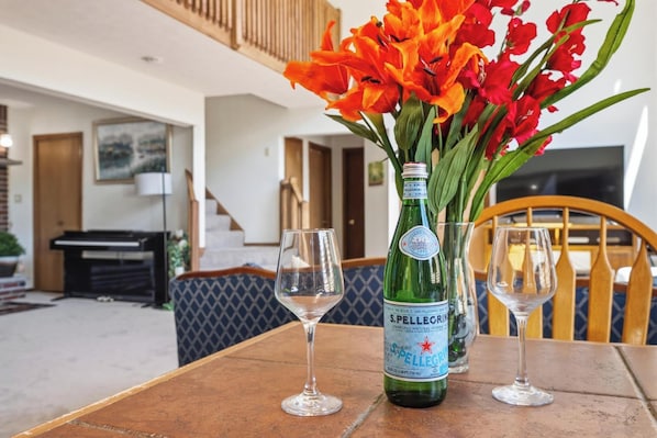 A table with a bottle of Pellegrino sparkling water, two glasses, and a vase of flowers.