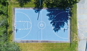Vue aérienne d’un terrain de basket-ball avec un panier, deux anneaux et une clôture qui l’entoure.